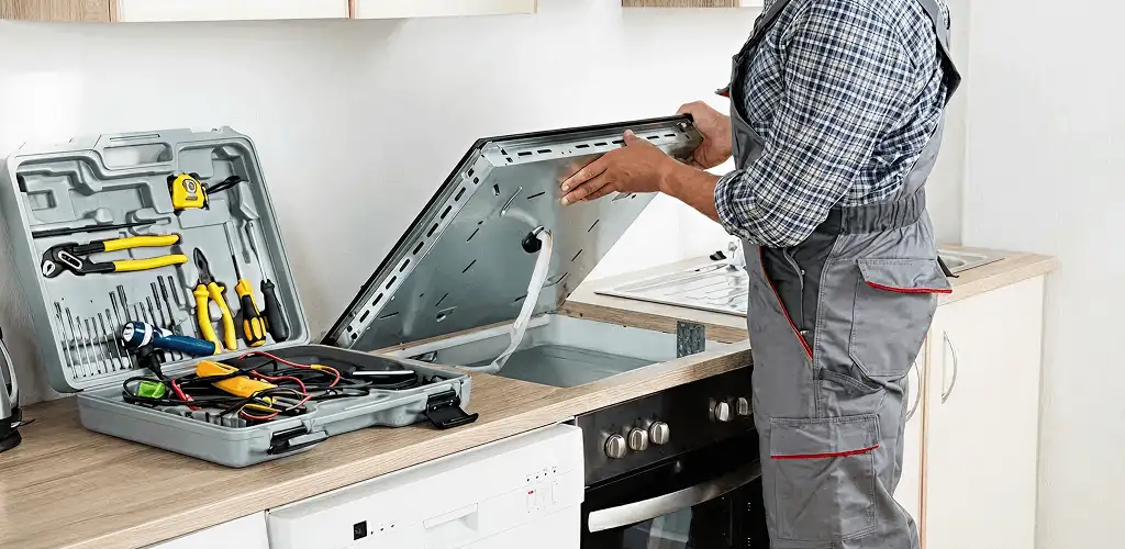 Handyman repairing a cooktop and checking wiring connections in Mobile, AL