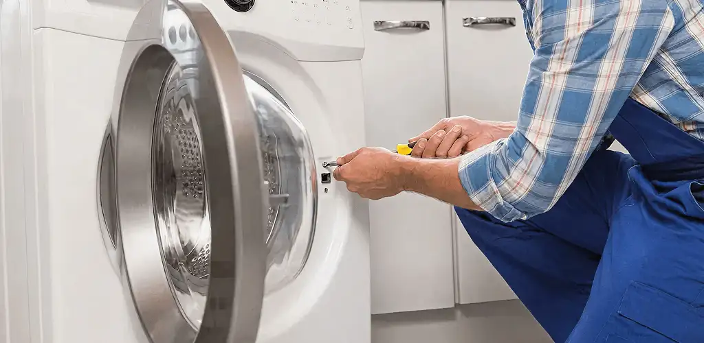 Handyman repairing a clothes dryer and checking electrical connections in Mobile, AL