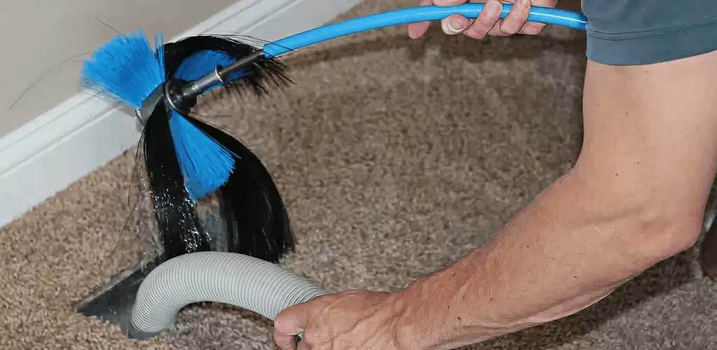 Dryer vent cleaning technician brushing lint from a vent line in Mobile, AL
