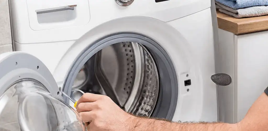 Handyman repairing a front-load washing machine and inspecting the drum in Mobile, AL