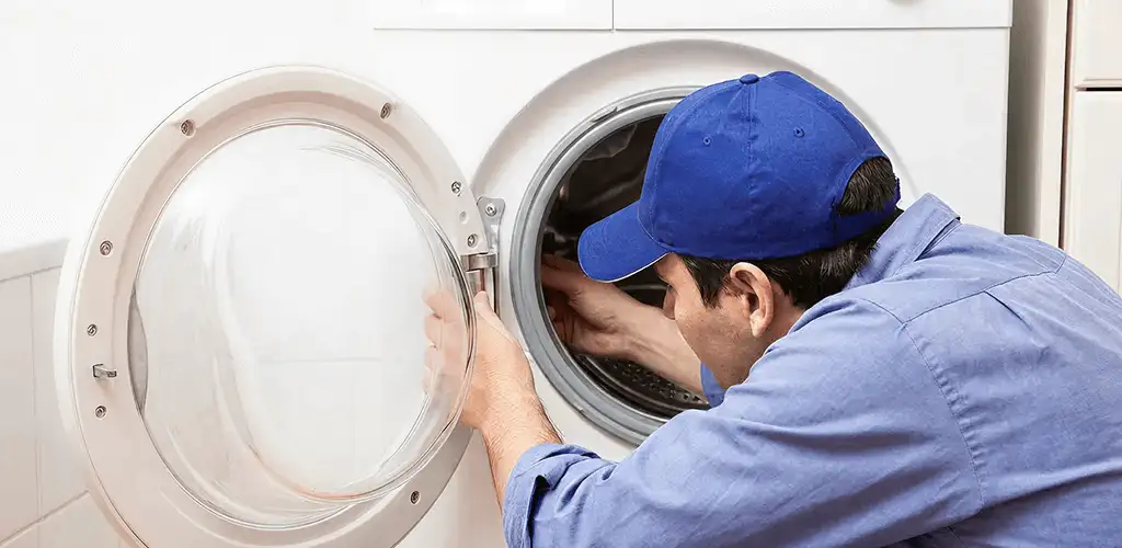 Washing machine repair handyman inspecting a front-load washer drum in Mobile, AL