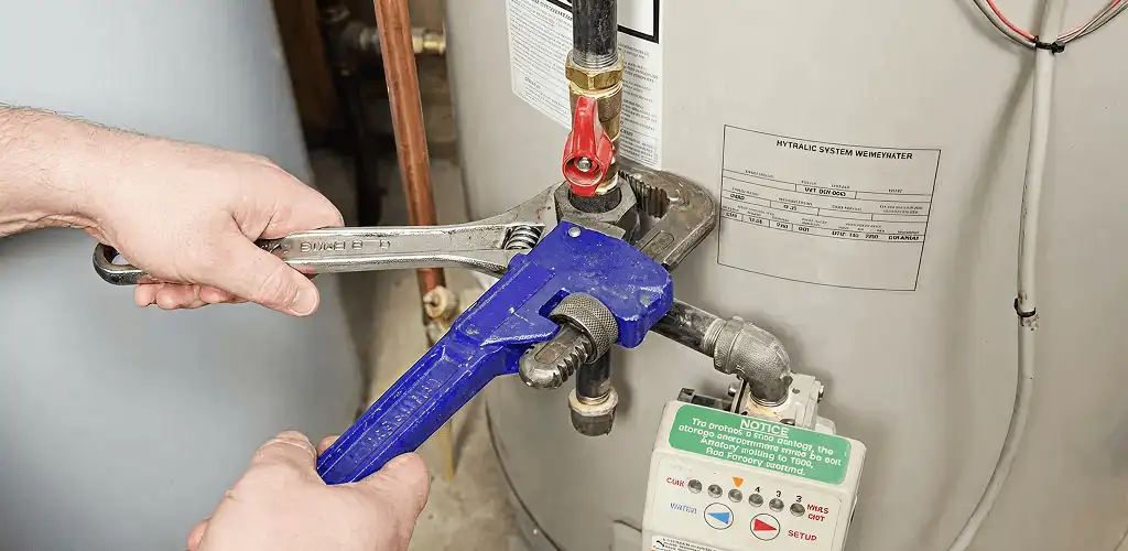 Water heater repair technician tightening the shutoff valve and supply line in Mobile, AL